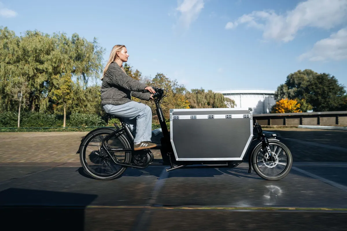 Vrouw rijdt op een vrachtfiets met dichte laadbak